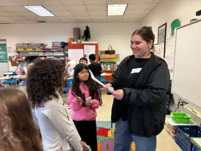 High school students smiling and teaching elementary students.